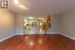 Unfurnished living room featuring track lighting, dark hardwood / wood-style flooring, and a textured ceiling - 