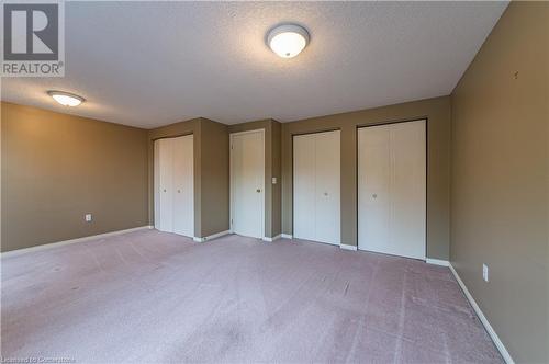 Unfurnished bedroom with a textured ceiling, light carpet, and two closets - 421 Beaver Creek Road, Waterloo, ON - Indoor Photo Showing Other Room