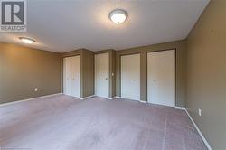 Unfurnished bedroom with a textured ceiling, light carpet, and two closets - 