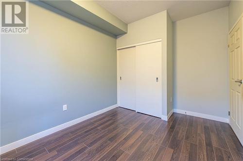 Unfurnished bedroom with dark wood-type flooring, a textured ceiling, and a closet - 62 Balsam Street Unit# T113, Waterloo, ON - Indoor Photo Showing Other Room