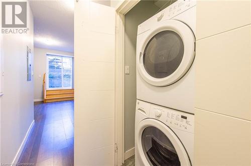 Laundry area with stacked washer / dryer, electric panel, wood-type flooring, and a textured ceiling - 62 Balsam Street Unit# T113, Waterloo, ON - Indoor Photo Showing Laundry Room