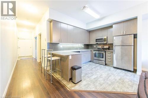 Kitchen with tasteful backsplash, stainless steel appliances, a breakfast bar, kitchen peninsula, and light hardwood / wood-style flooring - 62 Balsam Street Unit# T113, Waterloo, ON - Indoor Photo Showing Kitchen