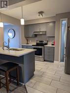 Kitchen featuring stainless steel appliances, kitchen peninsula, sink, gray cabinetry, and pendant lighting - 