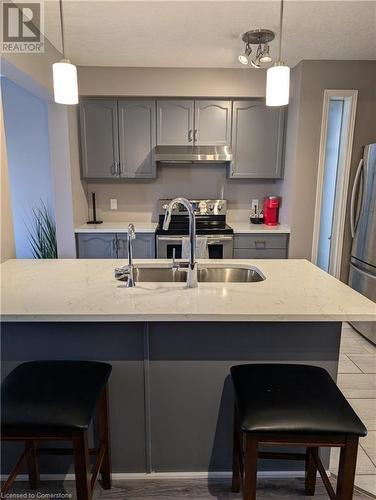 Kitchen featuring sink, light stone counters, appliances with stainless steel finishes, hanging light fixtures, and gray cabinets - 642 Inglis Falls Place, Waterloo, ON - Indoor Photo Showing Kitchen With Double Sink With Upgraded Kitchen