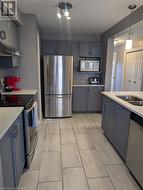 Kitchen featuring stainless steel appliances, light stone countertops, a textured ceiling, and pendant lighting - 