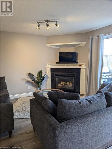 Living room featuring rail lighting, hardwood / wood-style floors, a tile fireplace, and a textured ceiling - 642 Inglis Falls Place, Waterloo, ON - Indoor Photo Showing Living Room With Fireplace