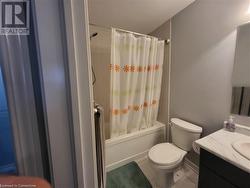 Full bathroom featuring tile patterned flooring, vanity, shower / bath combo with shower curtain, and toilet - 