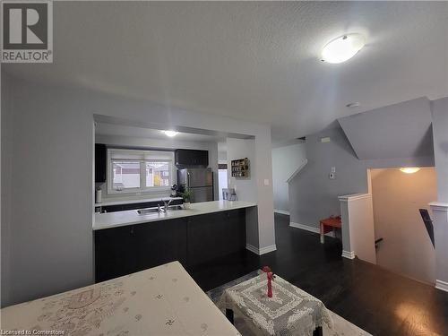 Kitchen featuring stainless steel fridge, dark hardwood / wood-style floors, sink, and a textured ceiling - 39 Appleby Street, Kitchener, ON - Indoor