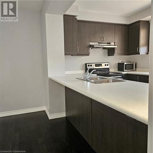 Kitchen featuring sink, stainless steel range, ventilation hood, hardwood / wood-style floors, and dark brown cabinets - 39 Appleby Street, Kitchener, ON - Indoor Photo Showing Kitchen With Double Sink