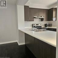 Kitchen featuring sink, stainless steel range, ventilation hood, hardwood / wood-style floors, and dark brown cabinets - 