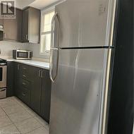 Kitchen with stainless steel fridge, stove, and light tile patterned flooring - 