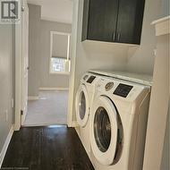 Laundry area with washer and clothes dryer, cabinets, and dark wood-type flooring - 