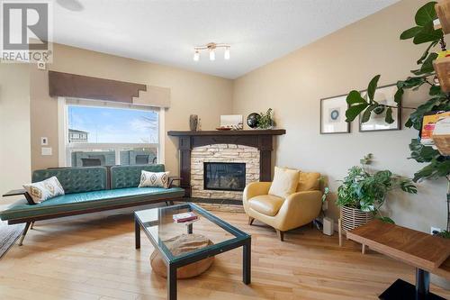 Cozy up by the elegant fireplace in the main floor living room, where large, bright windows offer stunning views of the expansive backyard - 111 Sage Hill Green Nw, Calgary, AB 