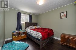 Bedroom with dark wood-type flooring and crown molding - 