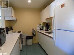 Kitchen featuring range hood, light tile patterned floors, sink, white cabinets, and white appliances - 