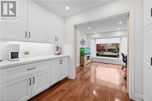 Bar with white cabinetry, wood-type flooring, and backsplash - 2401 Coventry Way, Burlington, ON 