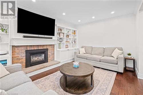 Living room with ornamental molding, dark hardwood / wood-style floors, and a brick fireplace - 2401 Coventry Way, Burlington, ON 