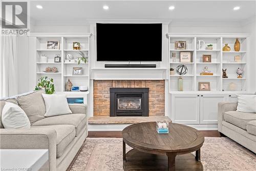 Living room featuring light wood-type flooring, ornamental molding, and a fireplace - 2401 Coventry Way, Burlington, ON 