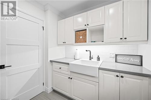 Kitchen featuring light hardwood / wood-style floors, white cabinetry, sink, ornamental molding, and tasteful backsplash - 2401 Coventry Way, Burlington, ON 