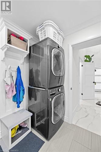 Clothes washing area featuring stacked washing maching and dryer and ornamental molding - 2401 Coventry Way, Burlington, ON 