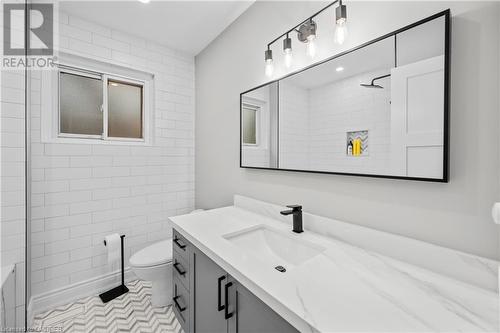 Bathroom featuring toilet, vanity, tile patterned floors, and tiled shower - 2401 Coventry Way, Burlington, ON 