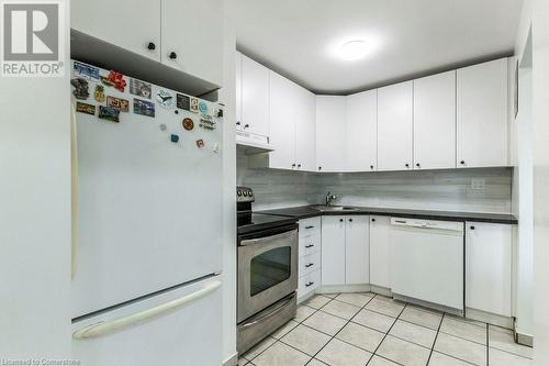 Kitchen with white cabinetry, white appliances, and decorative backsplash - 48 Windom Road Unit# E, Kitchener, ON 