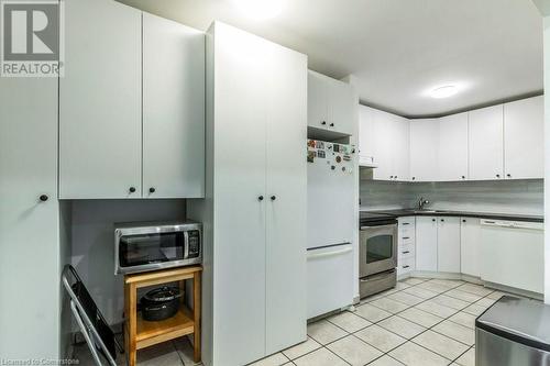 Kitchen featuring white cabinets, light tile patterned floors, sink, and appliances with stainless steel finishes - 48 Windom Road Unit# E, Kitchener, ON 