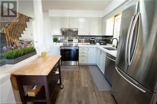 Kitchen featuring white cabinetry, sink, appliances with stainless steel finishes, tasteful backsplash, and dark wood-type flooring - 418 White Birch Avenue, Waterloo, ON 