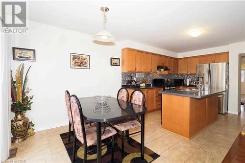 Kitchen featuring a center island with sink, stove, tasteful backsplash, pendant lighting, and stainless steel fridge - 89 Garth Massey Drive, Cambridge, ON - Indoor