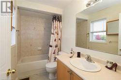 Full bathroom featuring vanity, shower / bath combo with shower curtain, and toilet - 