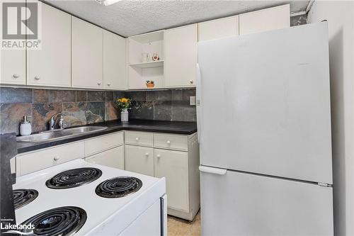 Kitchen featuring white cabinets, tasteful backsplash, sink, and white appliances - 72 57Th Street N, Wasaga Beach, ON 