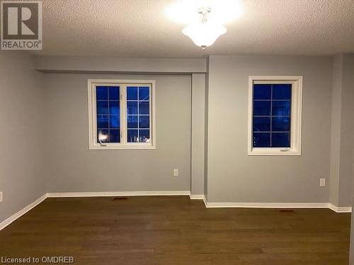 Empty room with dark wood-type flooring and a textured ceiling - 710 Spring Gardens Road Unit# 32, Burlington, ON 