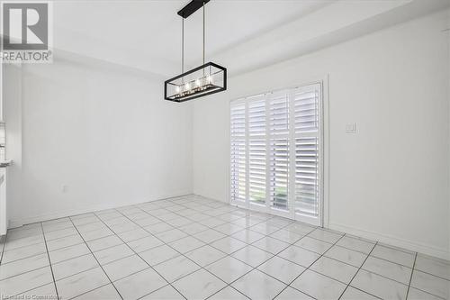 Unfurnished dining area featuring an inviting chandelier and light tile patterned floors - 21 White Star Lane, Grimsby, ON 