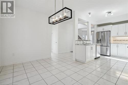 Kitchen featuring tasteful backsplash, appliances with stainless steel finishes, light tile patterned floors, sink, and white cabinets - 21 White Star Lane, Grimsby, ON 