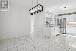 Kitchen featuring tasteful backsplash, appliances with stainless steel finishes, light tile patterned floors, sink, and white cabinets - 