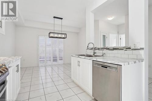 Kitchen featuring stainless steel appliances, white cabinetry, pendant lighting, light stone countertops, and sink - 21 White Star Lane, Grimsby, ON 