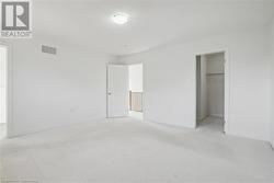 Unfurnished bedroom with light carpet, a walk in closet, and a closet - 