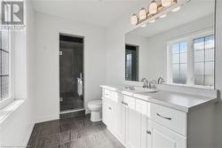 Bathroom featuring a shower with door, vanity, and toilet - 