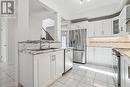 Kitchen featuring stainless steel appliances, white cabinetry, backsplash, light tile patterned floors, and sink - 21 White Star Lane, Grimsby, ON 