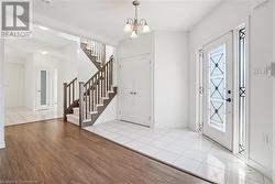 Foyer with light wood-type flooring, a wealth of natural light, and an inviting chandelier - 