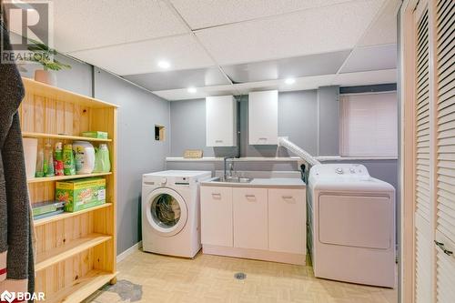 Laundry room with cabinets, sink, light parquet floors, and washer and clothes dryer - 47 Westfield Drive, St. Catharines, ON - Indoor Photo Showing Laundry Room