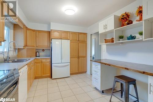 Kitchen with sink, a breakfast bar, light tile patterned floors, white appliances, and wood counters - 47 Westfield Drive, St. Catharines, ON - Indoor Photo Showing Kitchen With Double Sink