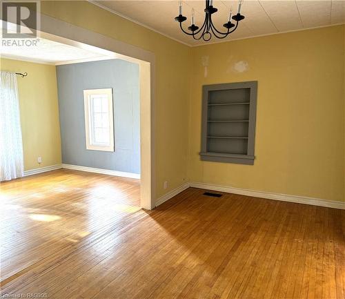 Spare room featuring an inviting chandelier, built in features, light hardwood / wood-style flooring, and ornamental molding - 941 20Th Street W, Georgian Bluffs, ON - Indoor Photo Showing Other Room