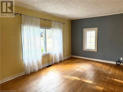 Unfurnished room with ornamental molding, light wood-type flooring, a textured ceiling, and a healthy amount of sunlight - 941 20Th Street W, Georgian Bluffs, ON - Indoor Photo Showing Other Room