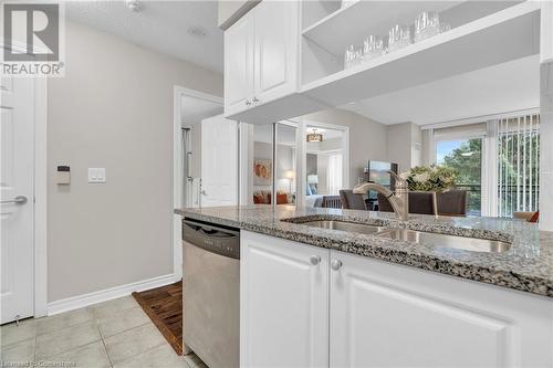 Kitchen featuring sink, light tile patterned flooring, stainless steel dishwasher, light stone countertops, and white cabinetry - 2379 Central Park Drive Unit# 206, Oakville, ON - Indoor Photo Showing Kitchen With Double Sink