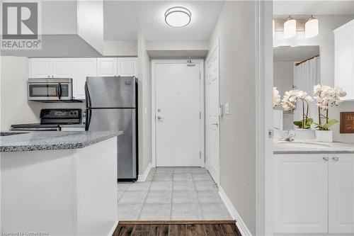 Kitchen featuring appliances with stainless steel finishes, light stone countertops, sink, white cabinets, and light hardwood / wood-style flooring - 2379 Central Park Drive Unit# 206, Oakville, ON - Indoor Photo Showing Kitchen