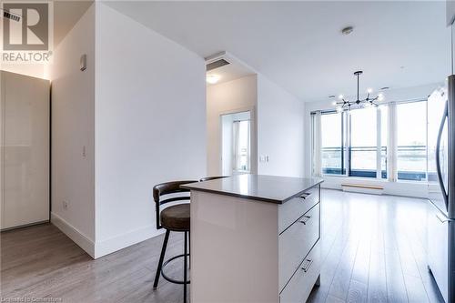 Kitchen with white cabinetry, refrigerator, decorative light fixtures, light hardwood / wood-style flooring, and a kitchen island - 15 Prince Albert Boulevard Unit# 610, Kitchener, ON - Indoor