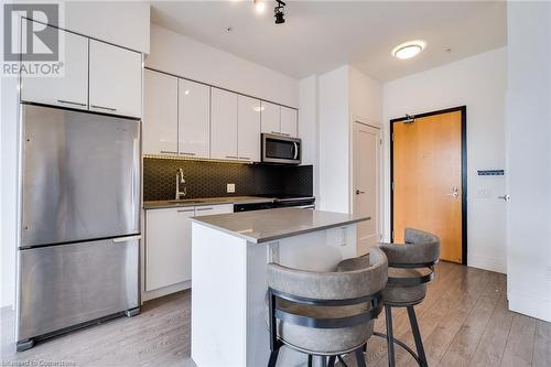 Kitchen with stainless steel appliances, a center island, a kitchen breakfast bar, white cabinetry, and light wood-type flooring - 15 Prince Albert Boulevard Unit# 610, Kitchener, ON - Indoor Photo Showing Kitchen