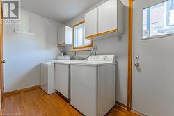 Laundry area with cabinets, washer and dryer, and light wood-type flooring - 