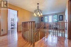 Stairway with wood-type flooring and a notable chandelier - 